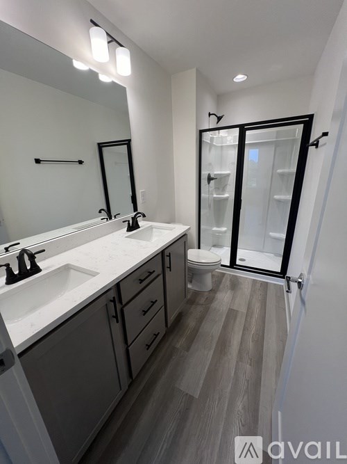 A bathroom with a sink, mirror, and a walk-in shower.