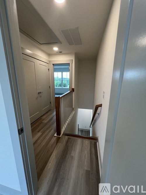 A hallway with a wooden floor and white walls.