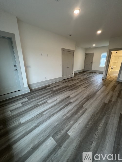 A spacious room with wooden flooring and white walls.