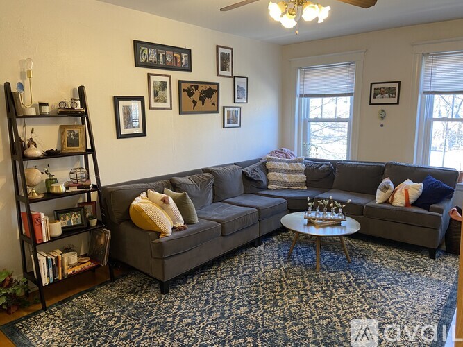 A living room with a grey couch, a coffee table, a bookshelf, and pictures on the wall.