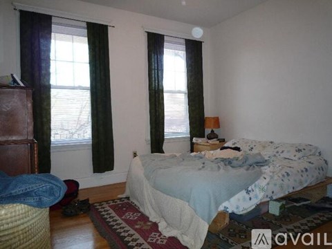 A bedroom with a bed, a dresser, and a window with curtains.