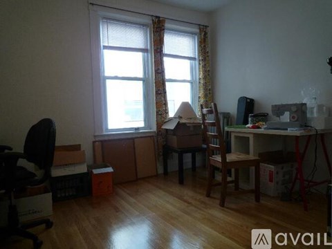 A room with a desk, chair, and boxes on the floor.