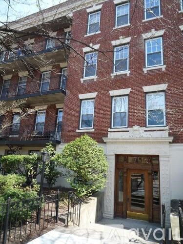 A red brick building with a black iron fence in front.