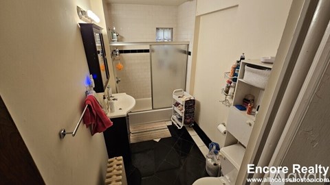 A small bathroom with a shower and a towel hanging on the door.