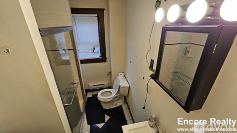 A bathroom with a toilet, sink, and mirror.