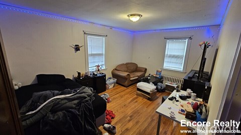A living room with a couch, chair, and a table with various items on it.