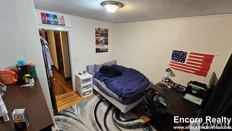A bedroom with a bed, desk, and American flag on the wall.