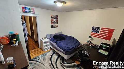 A bedroom with a bed, desk, and American flag on the wall.
