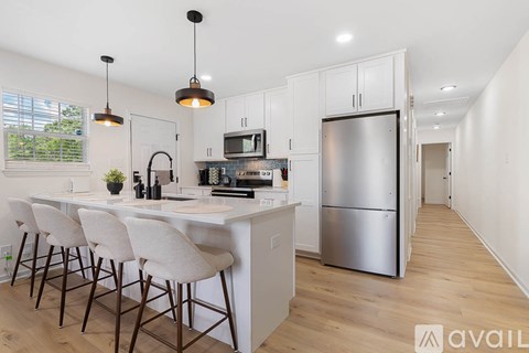 A kitchen with a white counter and bar stools.