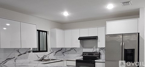 A kitchen with white cabinets and a marble counter top.