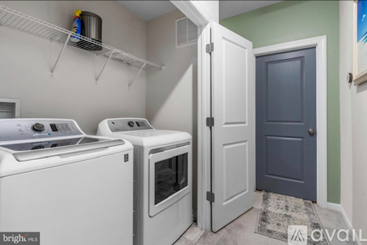 A kitchen with a white stove and oven, a white cabinet, and a white door.