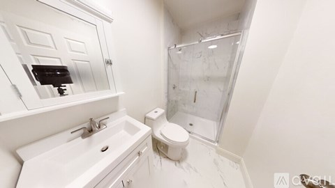 A white bathroom with a sink, toilet, and shower.