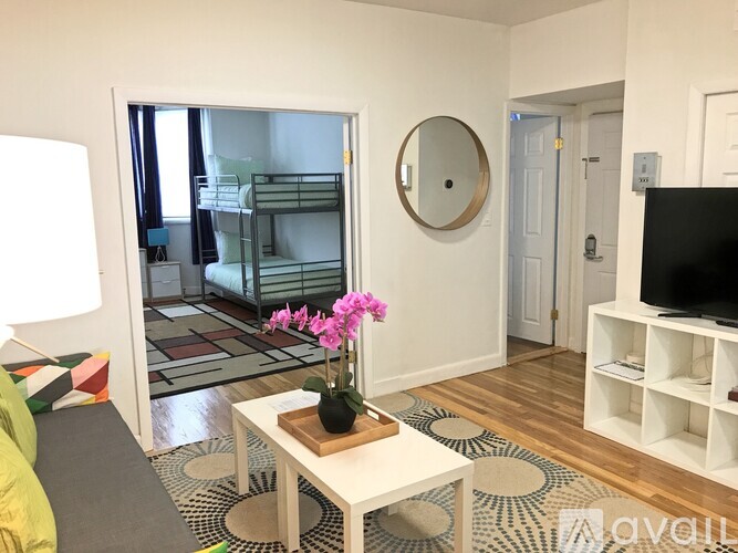A living room with a white coffee table and a round mirror on the wall.