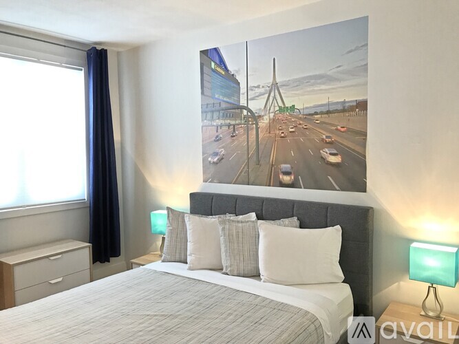 A bedroom with a large bed and a picture of a highway on the wall.