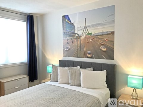 A bedroom with a large bed and a picture of a highway on the wall.