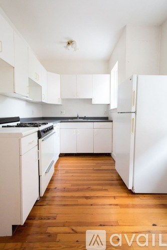 A kitchen with white appliances and wooden floors.