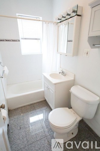 A white toilet sits in a bathroom with a white tub and sink.