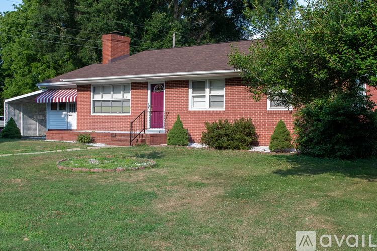 A red brick house with a white window and a red door.