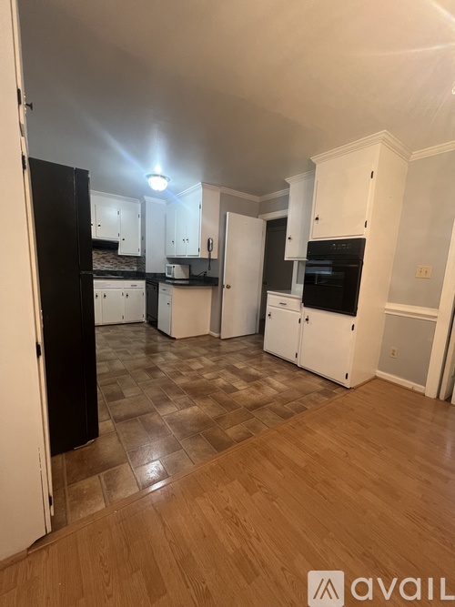 A kitchen with black appliances and white cabinets.
