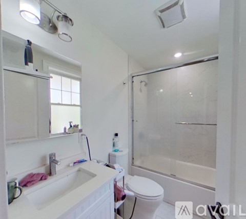 A white bathroom with a sink, toilet, and shower.