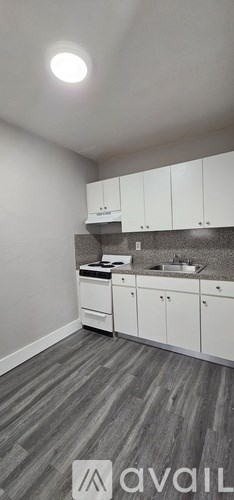 A kitchen with white cabinets and a grey floor.