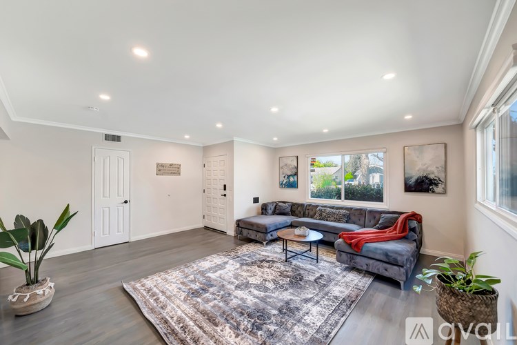A living room with a grey sofa and a rug in the middle.