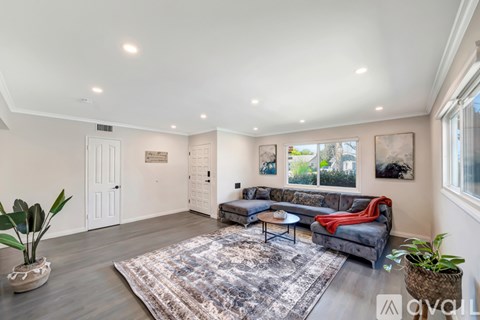 A living room with a grey sofa and a rug in the middle.