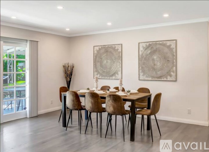 A dining room with a table set for six and two large circular artworks on the wall.