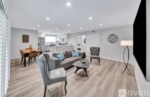 A modern living room with a grey sofa and a wooden dining table.