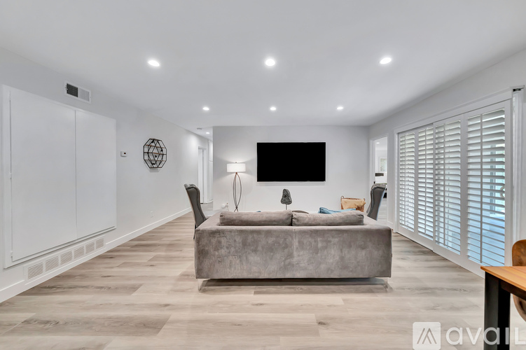 A modern living room with a grey sofa and a flat screen TV mounted on the wall.
