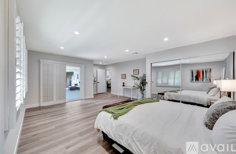 A bedroom with a large bed and a view of a hallway.