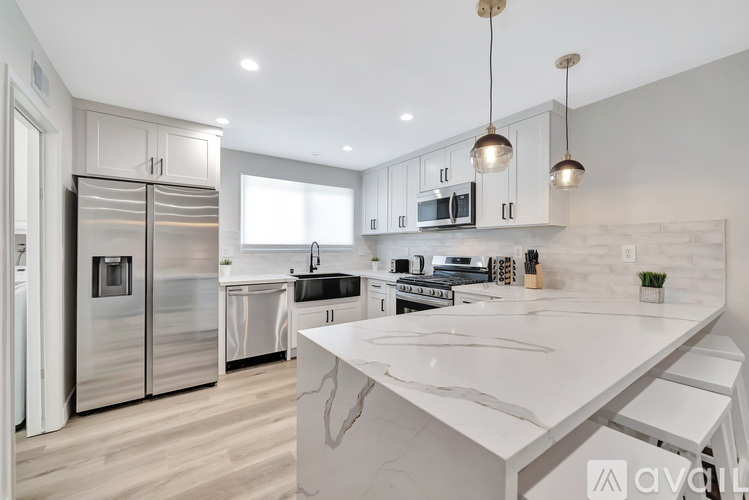 A modern kitchen with a marble countertop and stainless steel appliances.