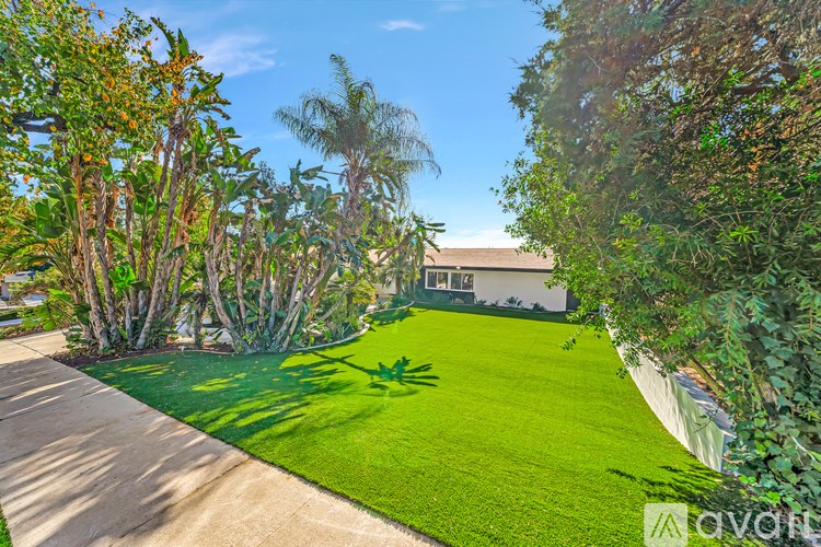 A well-manicured lawn with a pathway and trees in the background.