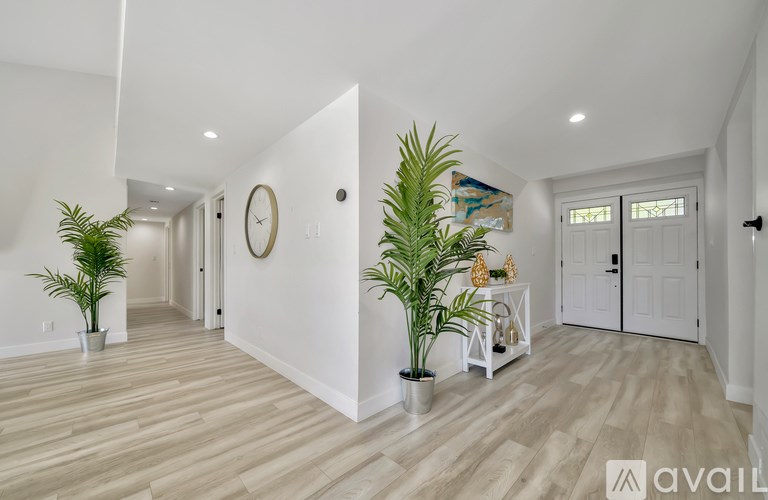 A living room with a wooden floor and a clock on the wall.
