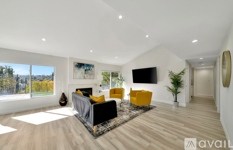 A living room with a grey couch, yellow chairs, and a flat screen TV mounted on the wall.