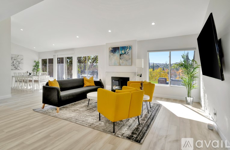 A modern living room with a black couch and yellow chairs.