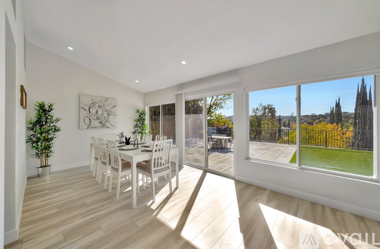 A dining room with a table set for six with a view of a tree-lined street outside.