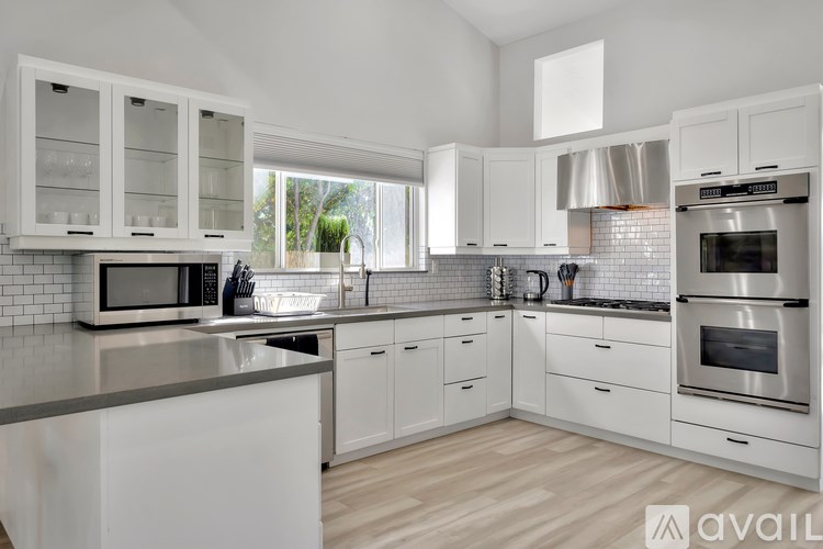 A modern kitchen with white cabinets and stainless steel appliances.