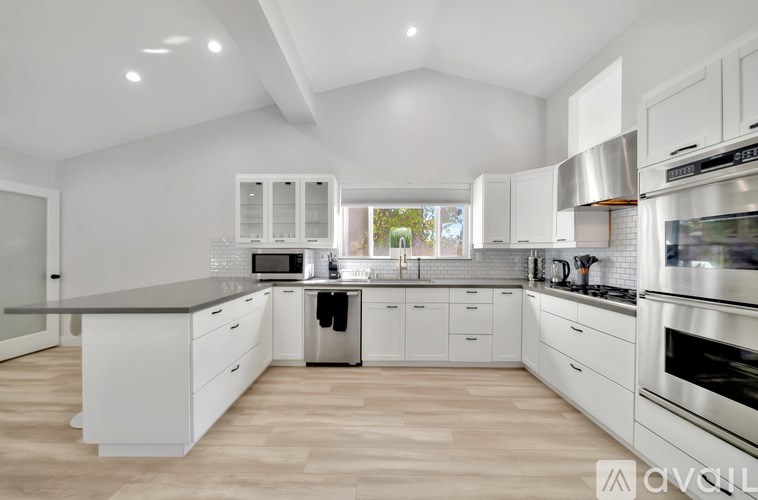 A modern kitchen with white cabinets and stainless steel appliances.
