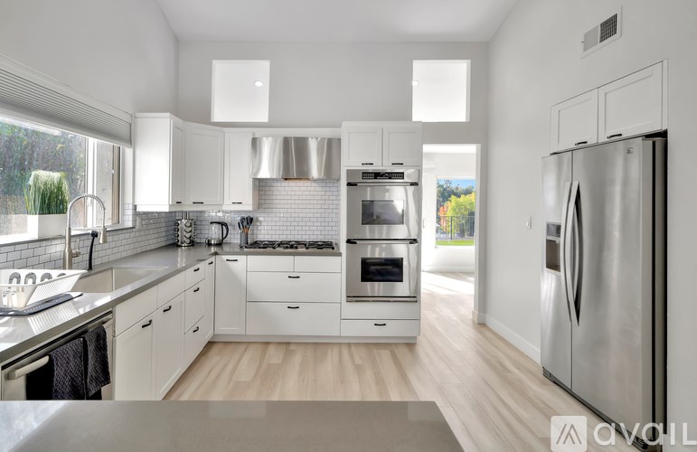 A modern kitchen with white cabinets and stainless steel appliances.