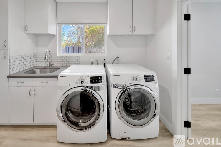 Two front load washing machines in a white laundry room.