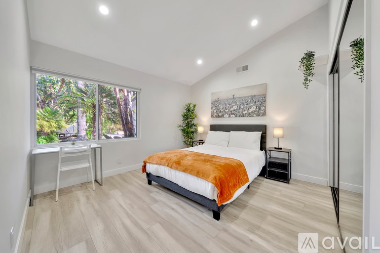 A bedroom with a large bed and a view of trees outside the window.