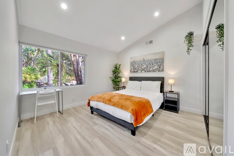 A bedroom with a large bed and a view of trees outside the window.