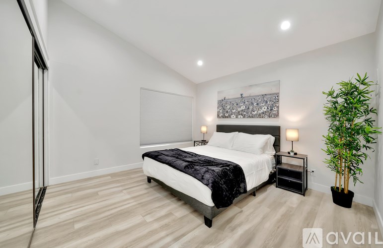 A bedroom with a bed, nightstands, and a plant.