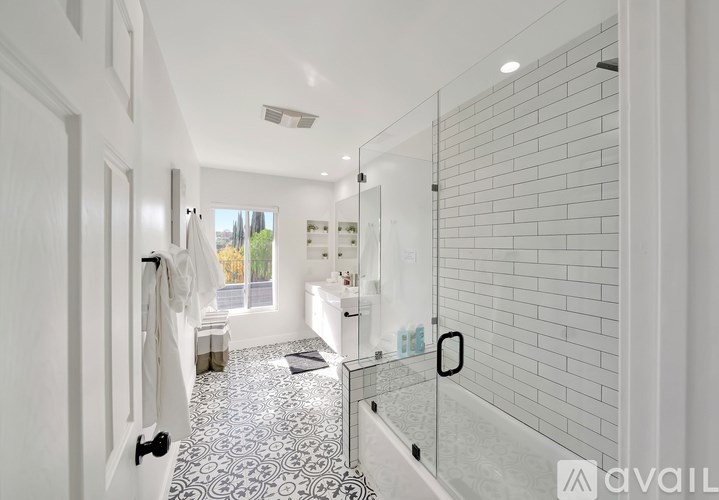 A bathroom with a glass shower door and a black and white tiled floor.