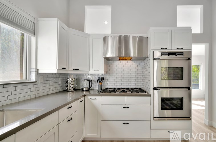 A modern kitchen with white cabinets and stainless steel appliances.