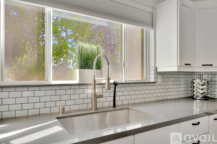 A modern kitchen with a large window and a stainless steel sink.