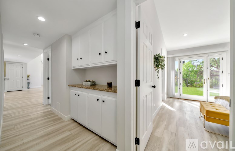 A modern kitchen with white cabinets and a wooden floor.