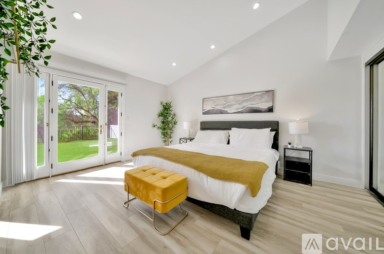 A bedroom with a large bed and a yellow ottoman.