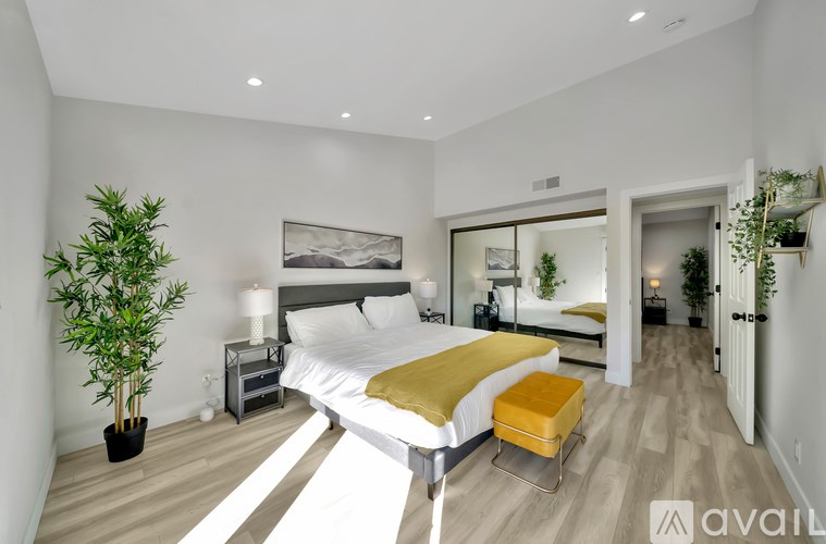 A bedroom with a large bed and a potted plant.